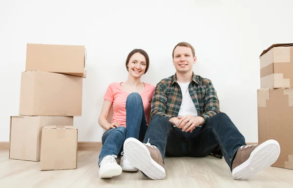 Man and woman sitting near cardboard boxes — Stock Photo, Image
