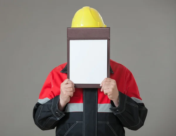 Construtor fechando seu rosto com prancheta — Fotografia de Stock