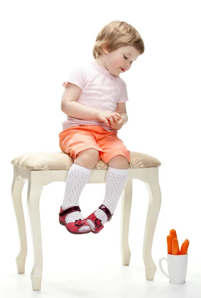 Girl on a banquette and looking at carrots — Stock Photo, Image