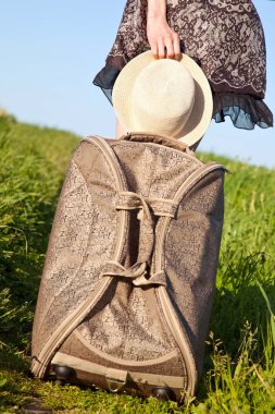 Şapka ve bir bavul tutan el