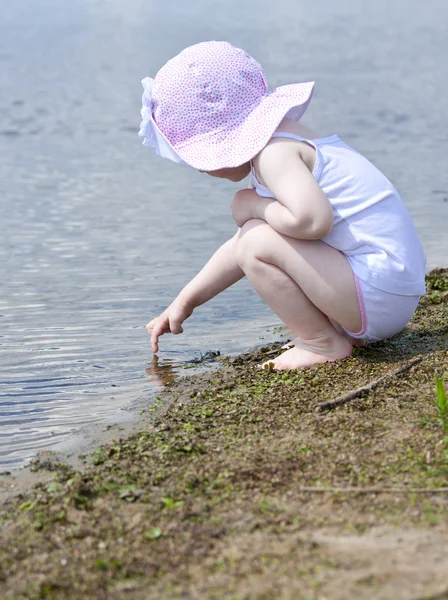 Fille assise sur le bord d'un lac — Photo