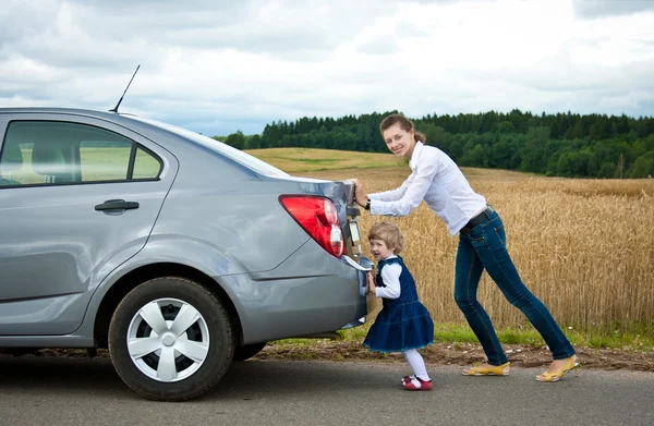 Filha ajuda mãe a empurrar carro — Fotografia de Stock