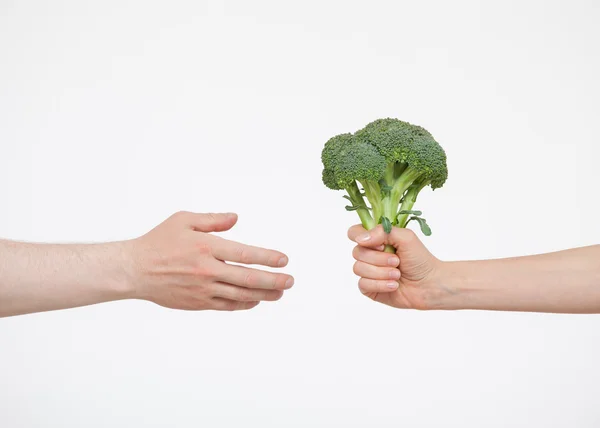 Hand gibt Brokkoli jemandem — Stockfoto