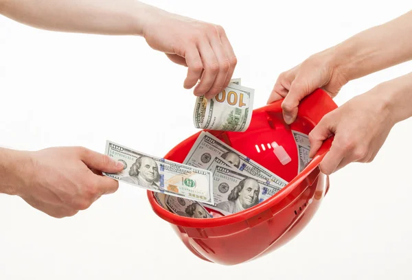 Hands putting dollars in a hard hat — Stock Photo, Image