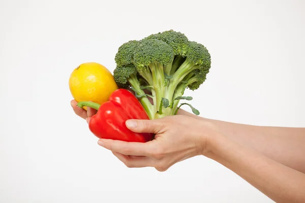 Manos sosteniendo brócoli, un limón y un pimiento rojo — Foto de Stock