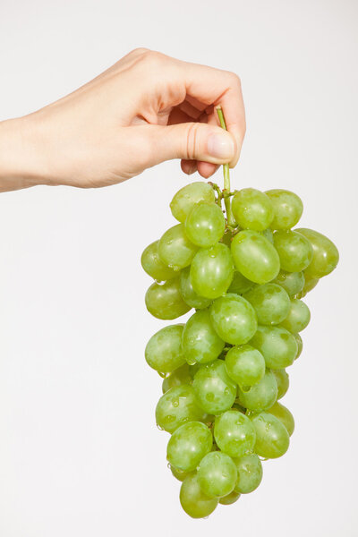 рука, держащая гроздь винограда
