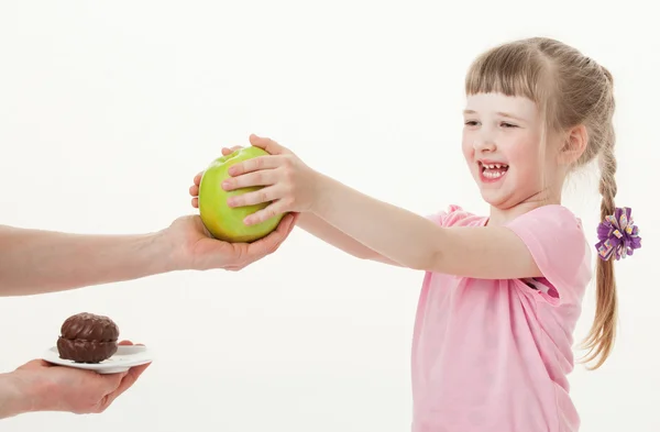 Mädchen wählt Apfel und lehnt Kuchen ab — Stockfoto