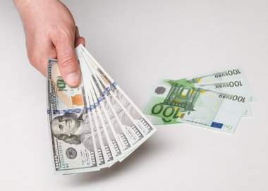 Hand holding dollars and euro banknotes on the table clipart