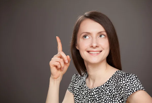 Glimlachende jonge vrouw die omhoog wijst — Stockfoto