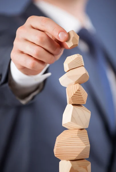 Businessman forming a wooden pyramid — Stock Photo, Image