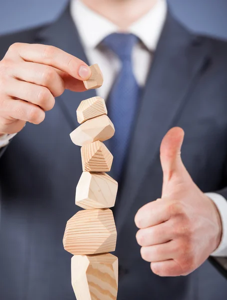 Geschäftsmann formt eine Holzpyramide — Stockfoto