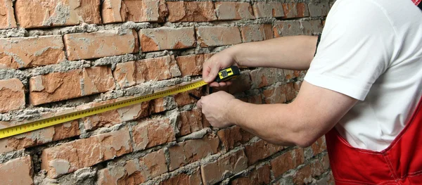 Constructor en uniforme con una cinta adhesiva —  Fotos de Stock