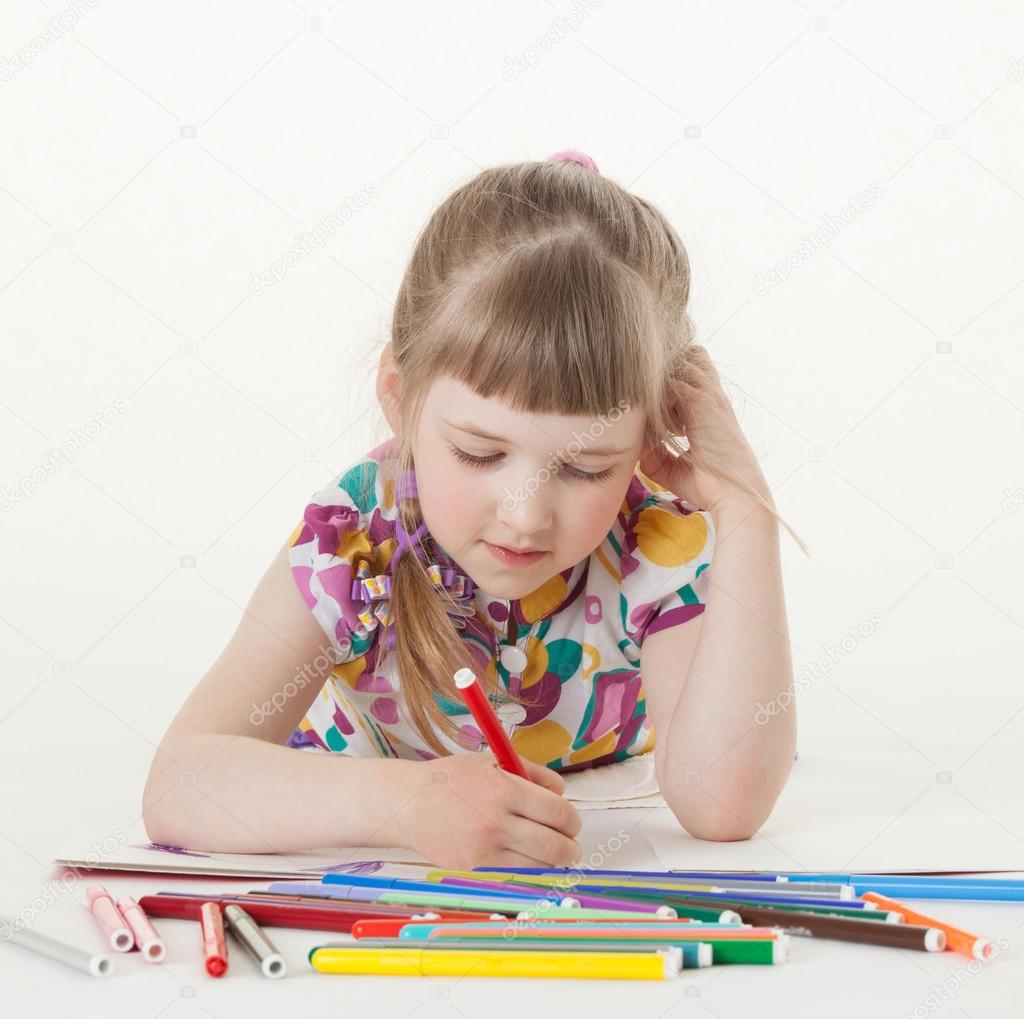 Little girl drawing and lying on the floor