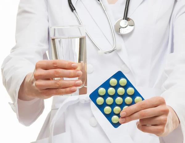 Médico segurando um copo de água e comprimidos — Fotografia de Stock