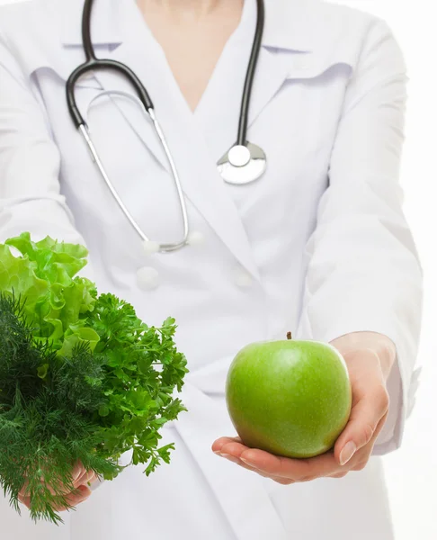 Diétariste proposant des légumes verts et une pomme — Photo