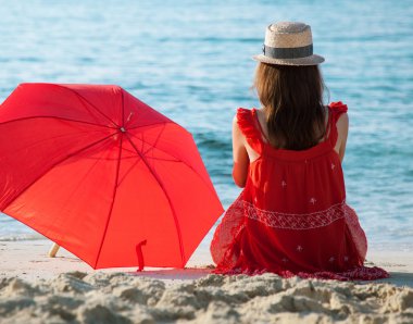 Kumlu sahilde oturan genç kadın