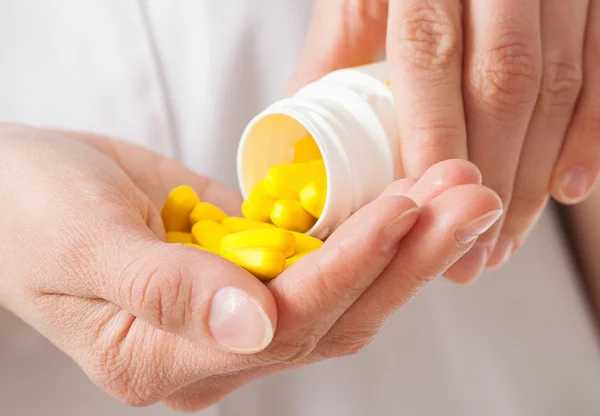 Doctor's pouring yellow tablets in the palm — Stock Photo, Image