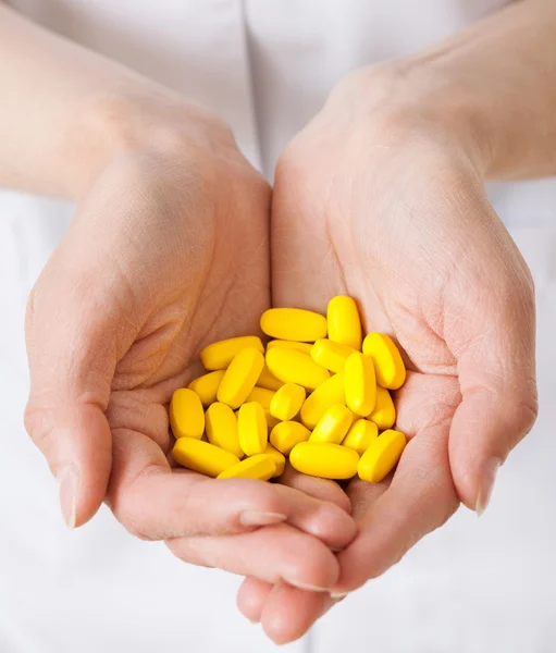 Doctor holding many yellow tablets — Stock Photo, Image