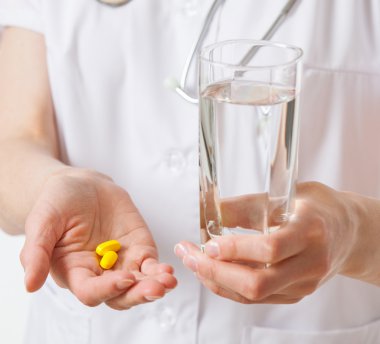 Doktor elinde bir bardak su tutuyor.