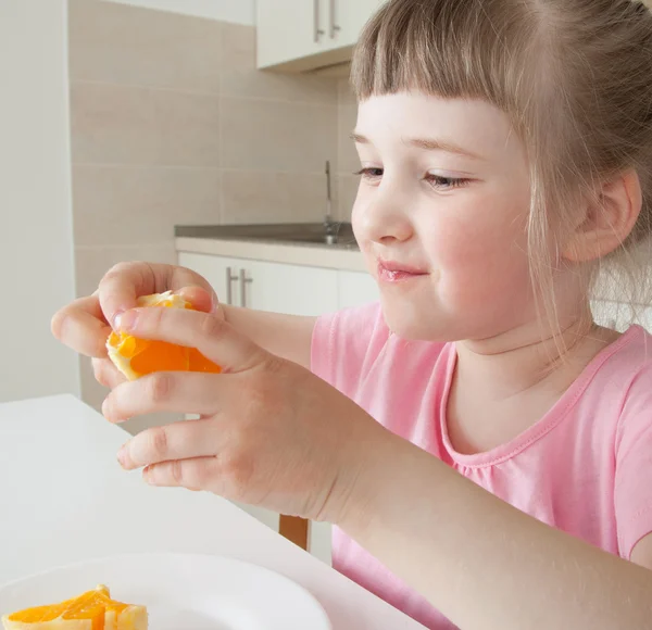 Glückliches kleines Mädchen isst eine leckere Orange — Stockfoto