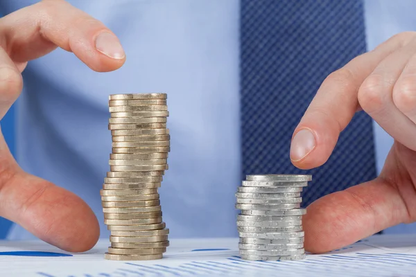 Businessman comparing stacks of coins — Stock Photo, Image