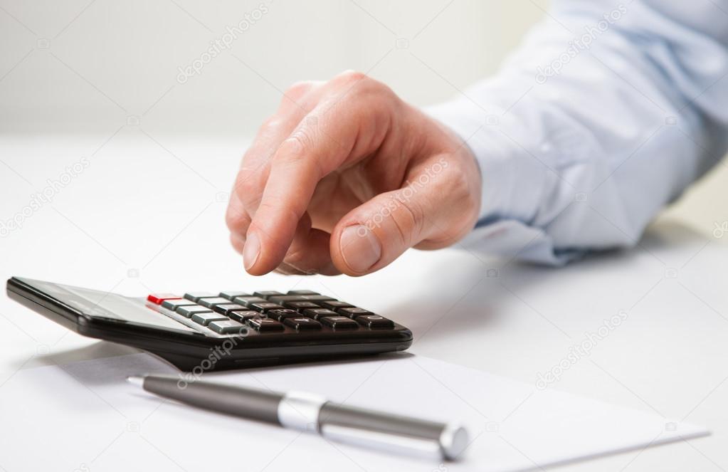 Hands of businessman using calculator