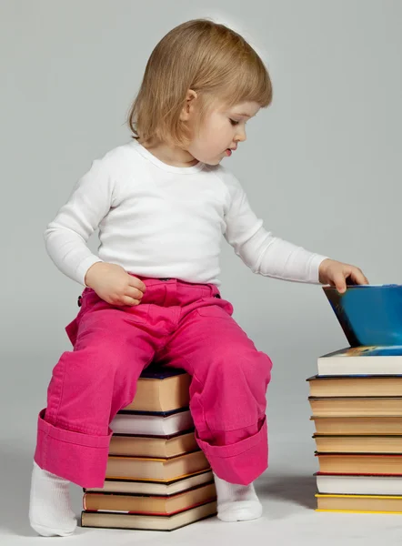 Dziecko siedzi ułożone książki — Zdjęcie stockowe