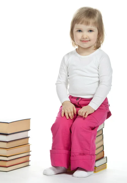 Девушка, сидящая на стопке книг — стоковое фото