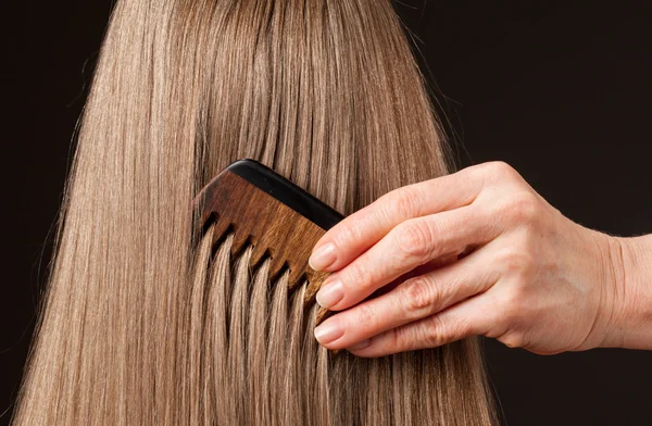 Female hand combing beautiful long hair — Stock Photo, Image