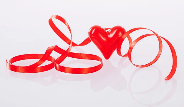 Twisted red ribbon and ceramic heart — Stock Photo, Image