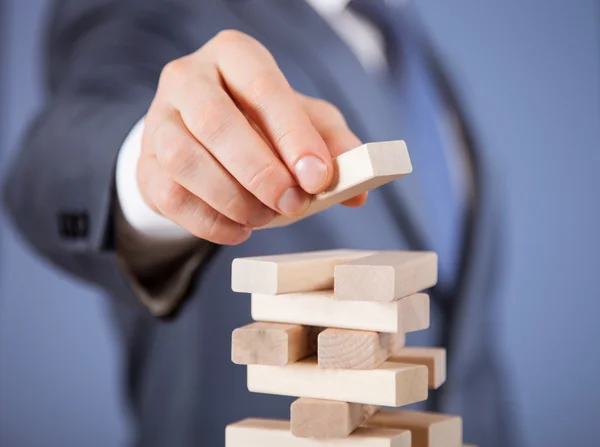 Uomo d'affari che forma una piramide di legno — Foto Stock