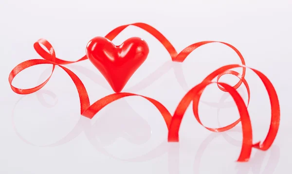 Twisted red ribbon and ceramic heart — Stock Photo, Image