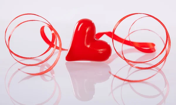 Στριμμένα κόκκινη κορδέλα και κεραμικά καρδιά — Φωτογραφία Αρχείου