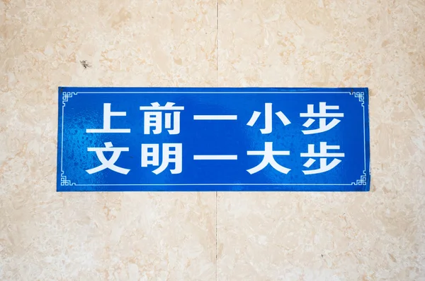 Chinesisches männliches Toilettenschild mit der Aufschrift "Ein kleiner Schritt vorwärts ist ein großer Schritt in Richtung Zivilisation"." — Stockfoto