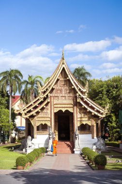 A young monk exits Wihan Lai Kham at Wat Phra Singh, Chiang Mai, Thailand