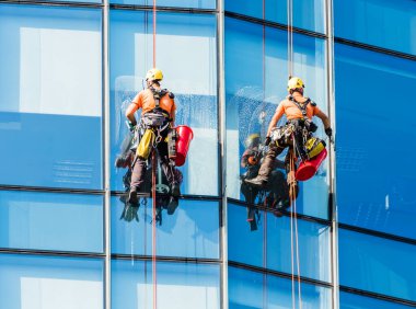 Yıkayıcılar modern gökdelenlerin camlarını siler. Pencere temizleyicisi modern gökdelenin cam cephesinde çalışıyor. Yüksek riskli iş.
