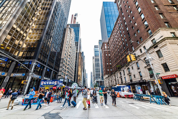 NEW YORK, USA - September 26, 2018: Crowd of people on Manhattan, New York. Traffic light, crosswalk and skyscrapers from Manhattan.