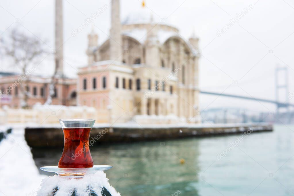 Snowy day in Ortakoy, Istanbul, Turkey. Turkish Tea with Ortakoy Mosque and Bosphorus Bridge background.