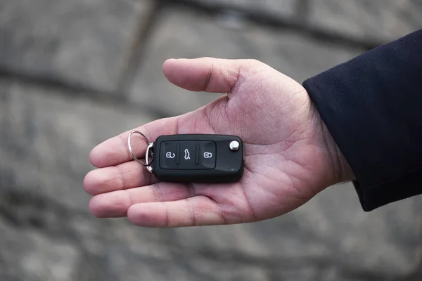 Man hand holding a car key. New car sell, auto showroom, car sale deal concepts. Black car key.