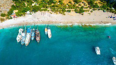 Oludeniz 'de Kelebek Vadisi (Türkçe: Kelebekler Vadisi). Kumsalda ve teknelerde insansız hava aracı var. Fethiye, Mugla, Türkiye.