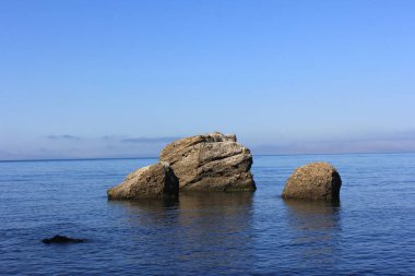 Kıyı kayaları bulutlu bir gökyüzüne karşı süzülüyor.