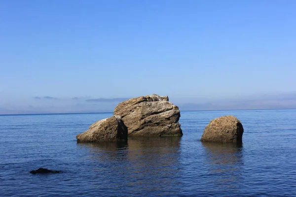 Kıyı kayaları bulutlu bir gökyüzüne karşı süzülüyor.