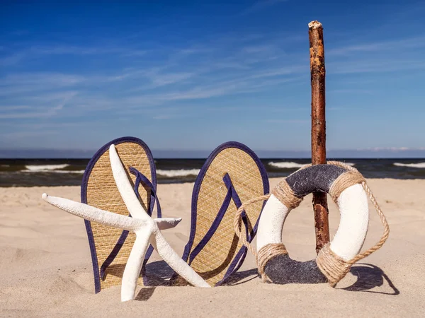 Flip-flops, livbojen och sjöstjärnor på stranden — Stockfoto
