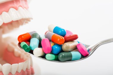 Beyaz arka plan ile sağlık tedavi için kaşık üzerinde uyuşturucu hap.