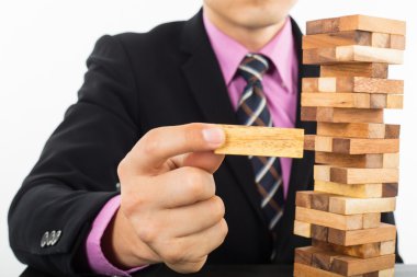 Odun Jenga oyununda iş riski kavramı. İş adamı stratejisini yönetir..