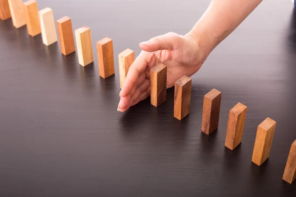 Stop domino risk effect ,businessman using hand for management solution.