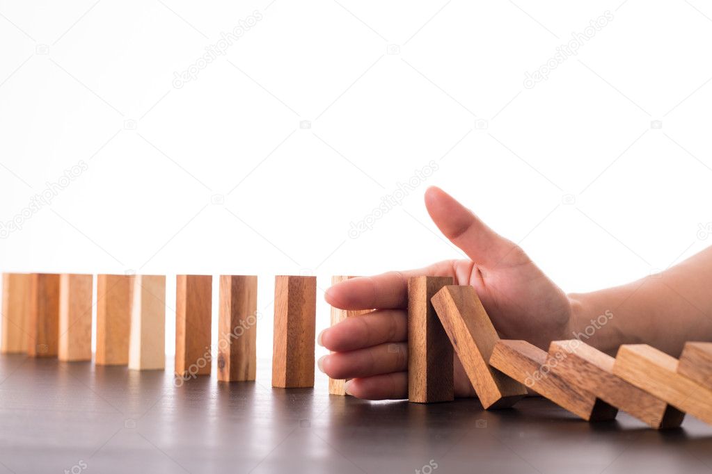 Stop domino risk effect ,businessman using hand for management solution.