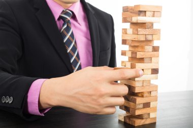 Odun Jenga oyununda iş riski kavramı. İş adamı stratejisini yönetir..