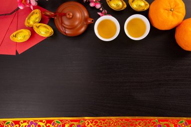 Flat lay Chinese new year mandarin orange and tea water with top view on black color wooden bakcground.Copy space  for celebrate china festival.hinese characters ZHAO CAI JIN BAO in the article refer to lucky fortune ,wealth, rich