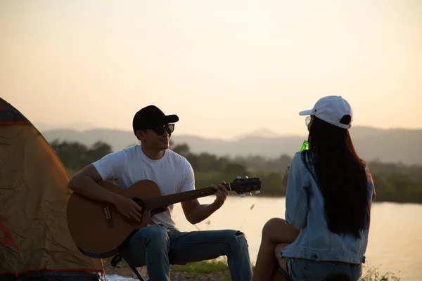 Asian couple playing guitar after finished camping tent in the outside.